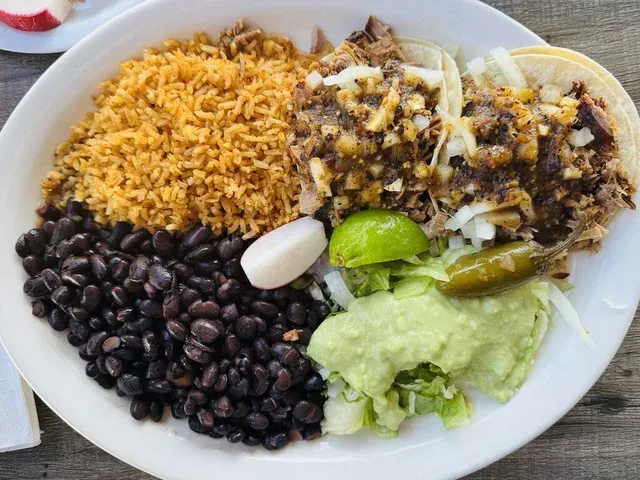 A carnitas plate with rice, beans, and guacamole