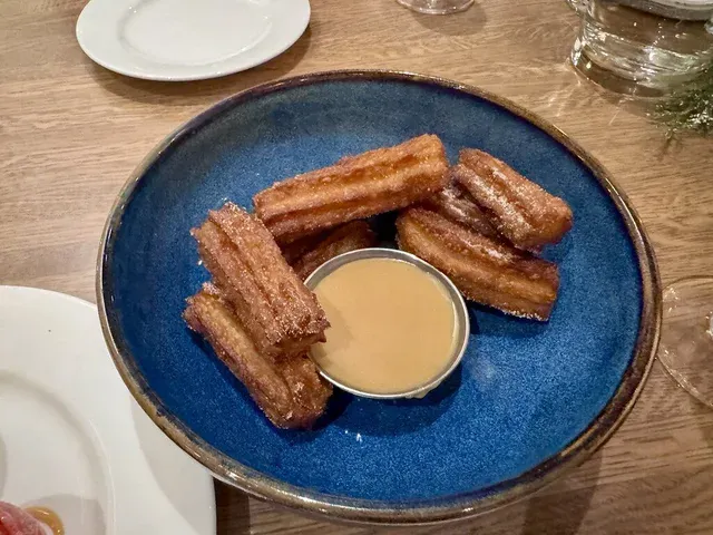 Churros with cajeta dipping sauce on a blue plate